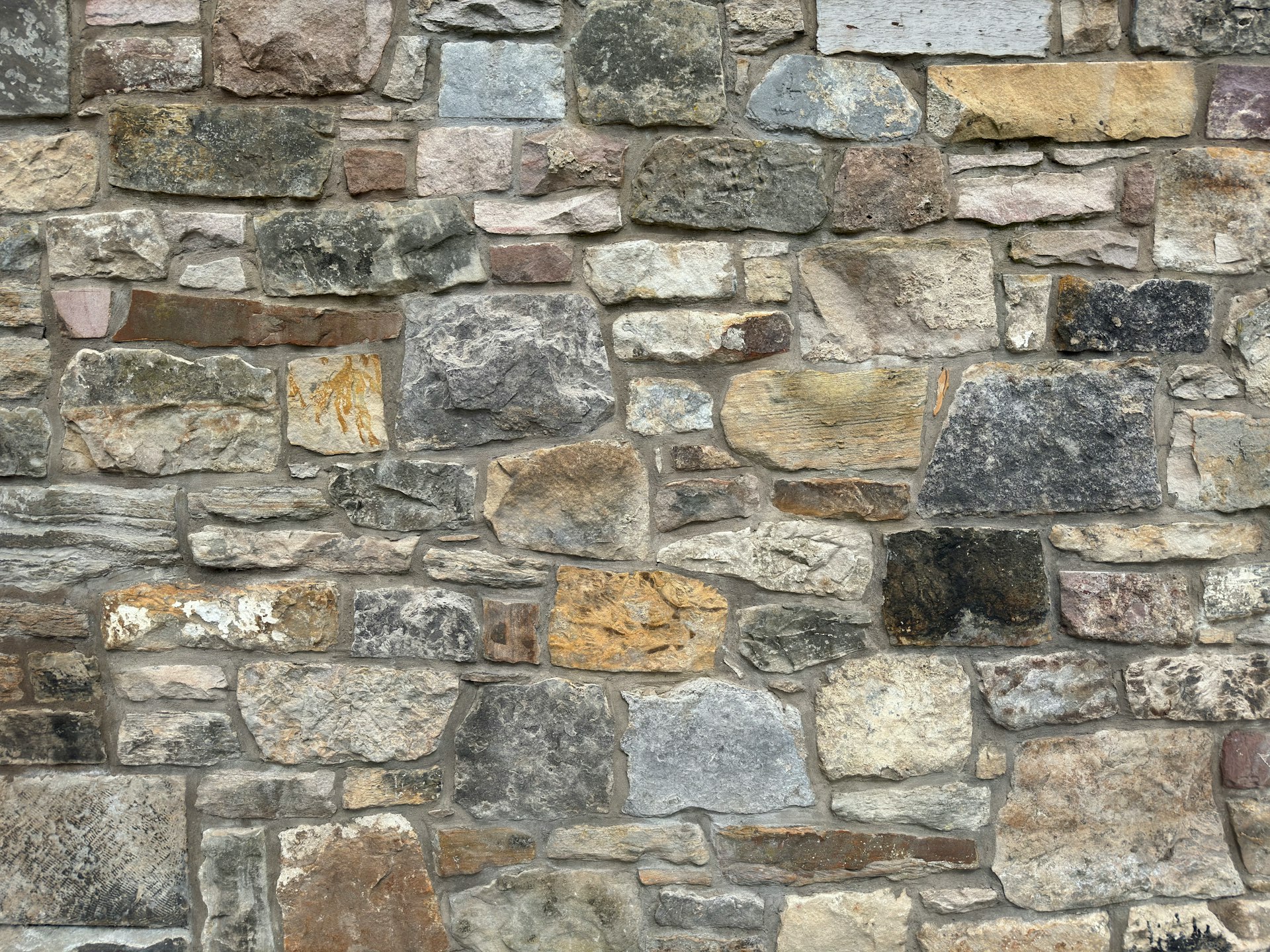 A close up of a stone wall with a clock on it